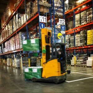 a forklift driving through a warehouse filled with pallets